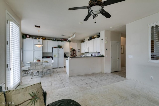 7836 Silver Plateau Ave, Las Vegas, NV 89128 - kitchen with white appliances, dark countertops, light tile patterned floors, a peninsula, and white cabinets