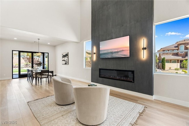 10707 Sleepy Mist Ct, Las Vegas, NV 89141 - living area featuring wood finished floors, a large fireplace, a high ceiling, and recessed lighting