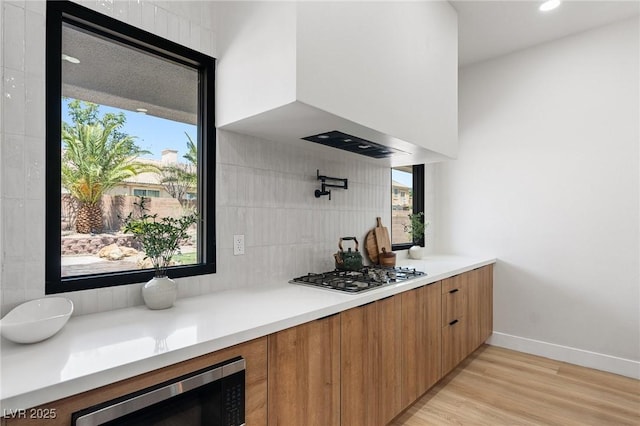 10707 Sleepy Mist Ct, Las Vegas, NV 89141 - kitchen with stainless steel appliances, modern cabinets, light wood finished floors, light countertops, and tasteful backsplash