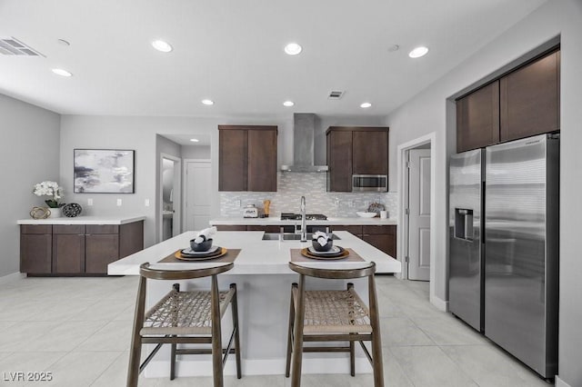 635 Pyrite Will St, Las Vegas, NV 89138 - kitchen with appliances with stainless steel finishes, wall chimney exhaust hood, light countertops, a kitchen breakfast bar, and dark brown cabinetry