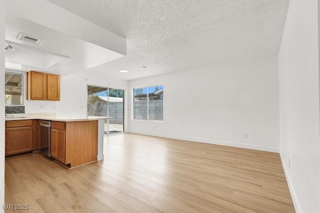 3908 Longfellow St, Las Vegas, NV 89115 - kitchen with a textured ceiling, a peninsula, stainless steel dishwasher, light wood finished floors, and open floor plan