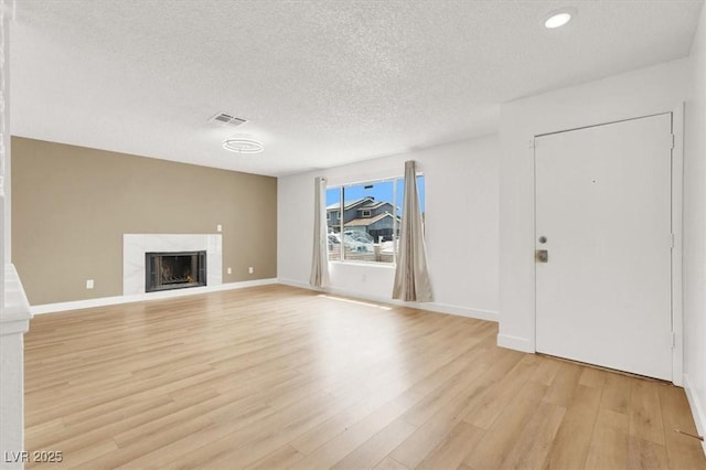 3908 Longfellow St, Las Vegas, NV 89115 - unfurnished living room featuring light wood-type flooring, a high end fireplace, a textured ceiling, and recessed lighting