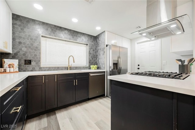 1712 E Oakey Blvd, Las Vegas, NV 89104 - kitchen featuring appliances with stainless steel finishes, exhaust hood, light wood-style flooring, light countertops, and white cabinetry