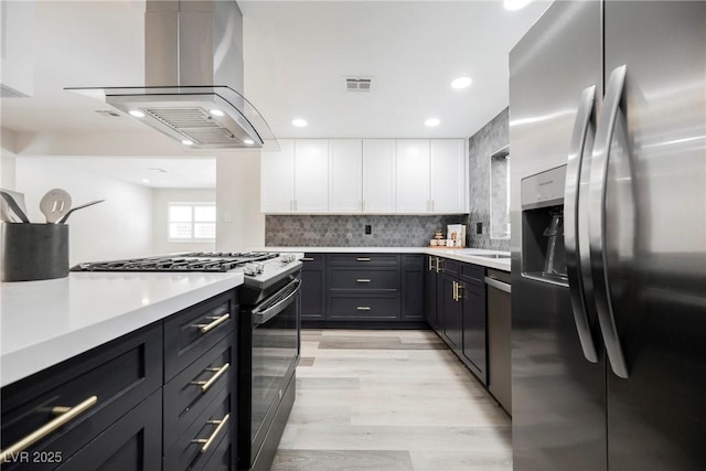 1712 E Oakey Blvd, Las Vegas, NV 89104 - kitchen with appliances with stainless steel finishes, exhaust hood, white cabinets, light countertops, and light wood-style flooring
