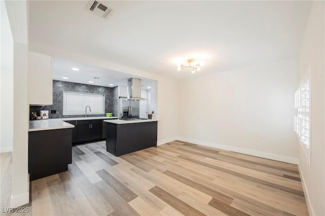 1712 E Oakey Blvd, Las Vegas, NV 89104 - kitchen with wall chimney exhaust hood, light countertops, a chandelier, dark cabinets, and light wood-type flooring