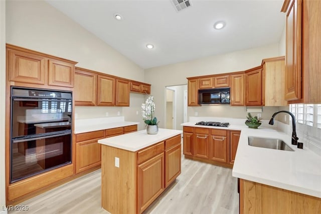 1078 Broomfield Dr, Henderson, NV 89074 - kitchen featuring black appliances, light wood-type flooring, light countertops, lofted ceiling, and a center island