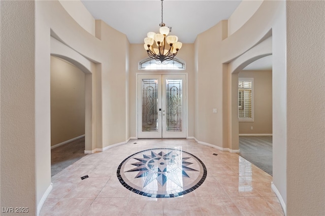 9208 Brilliant Ore Dr, Las Vegas, NV 89143 - foyer featuring arched walkways, inlaid floor details, a chandelier, a high ceiling, and tile patterned floors