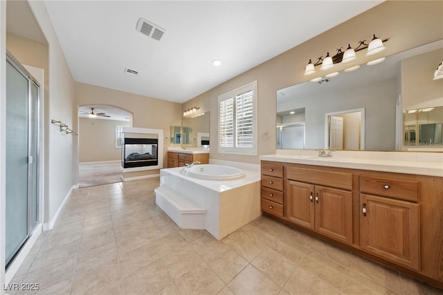 9208 Brilliant Ore Dr, Las Vegas, NV 89143 - bathroom featuring a stall shower, vanity, a bath, a multi sided fireplace, and tile patterned floors