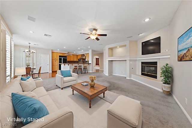 9208 Brilliant Ore Dr, Las Vegas, NV 89143 - living area with a chandelier, a ceiling fan, a glass covered fireplace, recessed lighting, and light carpet