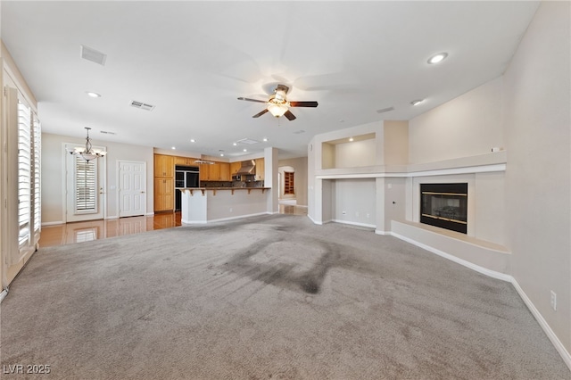9208 Brilliant Ore Dr, Las Vegas, NV 89143 - unfurnished living room featuring a ceiling fan, a glass covered fireplace, a chandelier, recessed lighting, and light carpet