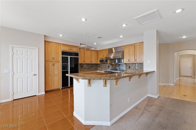 9208 Brilliant Ore Dr, Las Vegas, NV 89143 - kitchen featuring black refrigerator, wall chimney range hood, arched walkways, a kitchen bar, and a peninsula