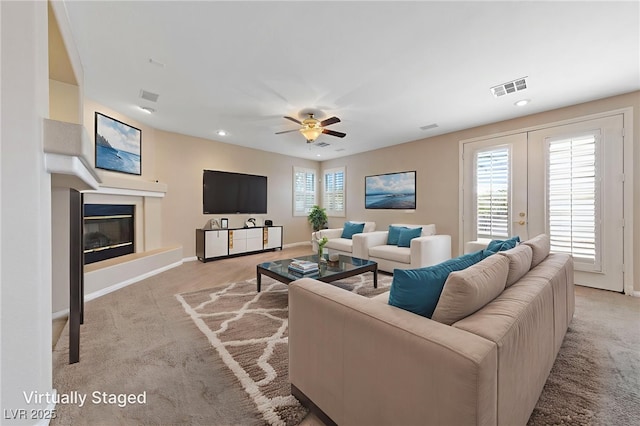 9208 Brilliant Ore Dr, Las Vegas, NV 89143 - living area with carpet flooring, a glass covered fireplace, ceiling fan, recessed lighting, and french doors