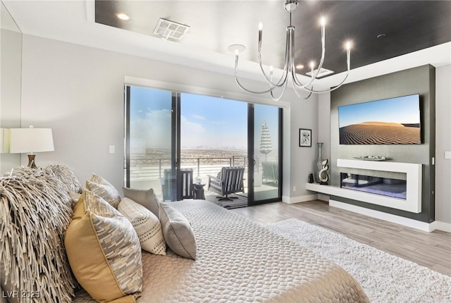426 Tranquil Peak Ct, Henderson, NV 89012 - bedroom with a chandelier, access to outside, wood finished floors, and a glass covered fireplace