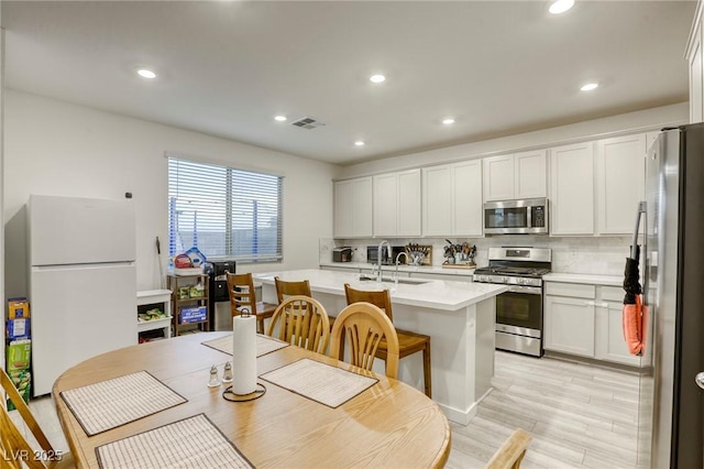 2807 Lindsey Springs St, Las Vegas, NV 89142 - kitchen featuring stainless steel appliances, decorative backsplash, light countertops, an island with sink, and recessed lighting