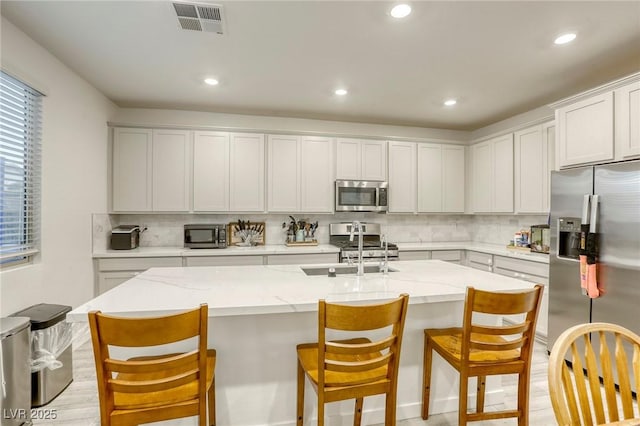 2807 Lindsey Springs St, Las Vegas, NV 89142 - kitchen with stainless steel appliances, tasteful backsplash, recessed lighting, a kitchen island with sink, and a kitchen bar