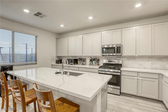 2807 Lindsey Springs St, Las Vegas, NV 89142 - kitchen featuring appliances with stainless steel finishes, tasteful backsplash, a center island with sink, a breakfast bar area, and recessed lighting