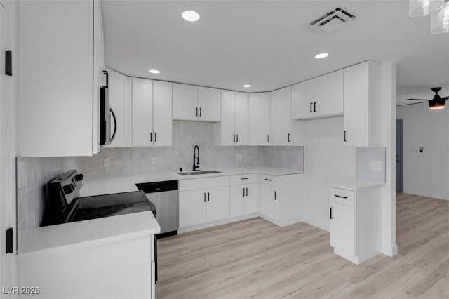 6340 Factor Ave, Las Vegas, NV 89107 - kitchen with appliances with stainless steel finishes, ceiling fan, tasteful backsplash, white cabinets, and light wood-style flooring