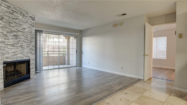 2200 S Fort Apache Rd Unit 1025, Las Vegas, NV 89117 - unfurnished living room featuring a textured ceiling, a fireplace, and wood finished floors