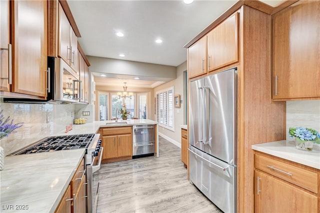 10800 Albright Pl, Las Vegas, NV 89134 - kitchen with appliances with stainless steel finishes, a peninsula, light wood finished floors, backsplash, and light countertops