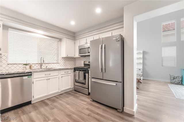 77 Huntfield Dr, Henderson, NV 89074 - kitchen with appliances with stainless steel finishes, white cabinetry, light wood finished floors, decorative backsplash, and recessed lighting