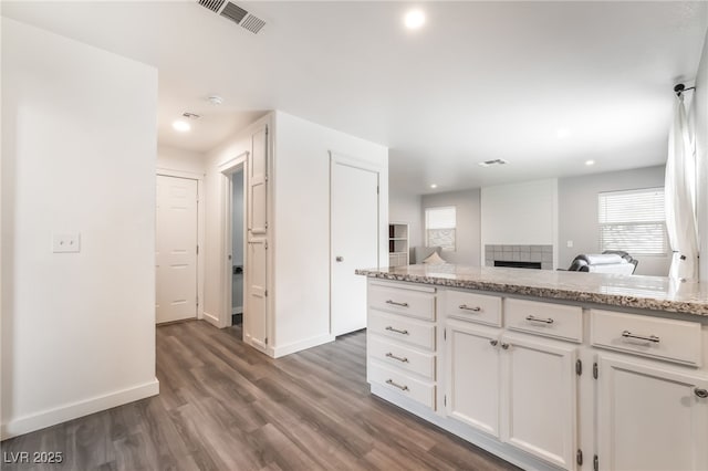 77 Huntfield Dr, Henderson, NV 89074 - kitchen with white cabinets, dark wood-style flooring, recessed lighting, a fireplace, and light stone counters