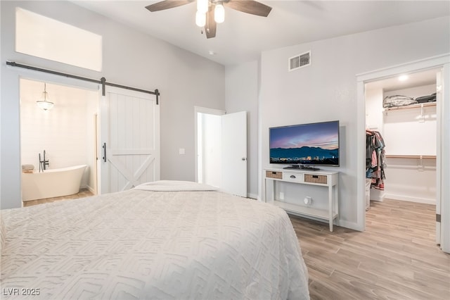 77 Huntfield Dr, Henderson, NV 89074 - bedroom featuring light wood-type flooring, a spacious closet, a barn door, a closet, and a ceiling fan
