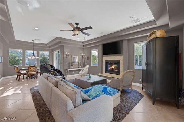 3668 Hillary Elan Ct, Las Vegas, NV 89139 - living area featuring a tray ceiling, light tile patterned floors, a glass covered fireplace, and healthy amount of natural light