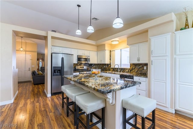 5620 Silver Belle St, Las Vegas, NV 89149 - kitchen featuring stainless steel appliances, backsplash, dark wood-style flooring, white cabinetry, and a breakfast bar