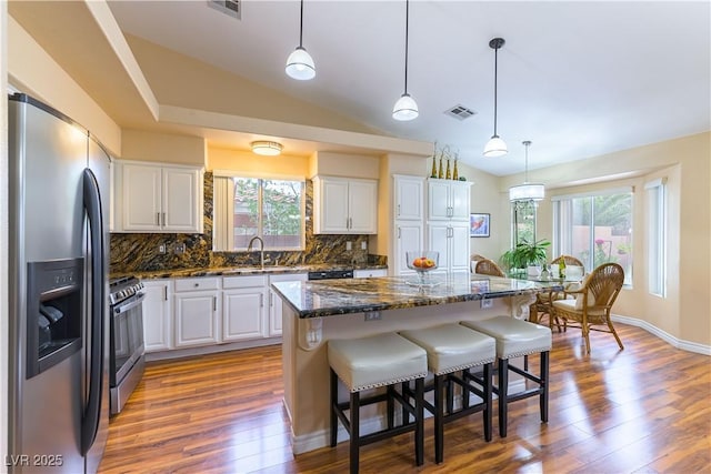 5620 Silver Belle St, Las Vegas, NV 89149 - kitchen featuring appliances with stainless steel finishes, backsplash, white cabinets, healthy amount of natural light, and lofted ceiling