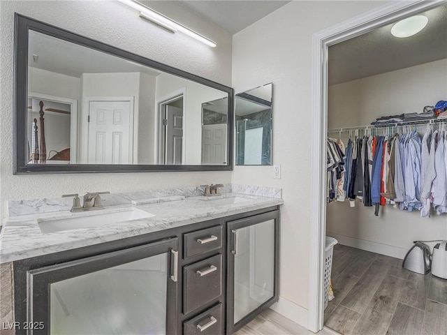 7375 Emerald Glow St, Las Vegas, NV 89123 - bathroom featuring double vanity, wood finished floors, and a walk in closet