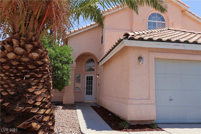 6492 Silent Pine Ave, Las Vegas, NV 89156 - view of exterior entry with a tiled roof, a garage, and stucco siding