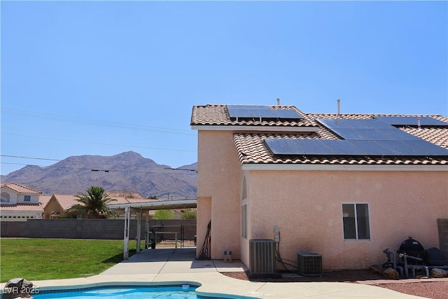6492 Silent Pine Ave, Las Vegas, NV 89156 - back of house featuring stucco siding, a mountain view, solar panels, a fenced backyard, and a patio area