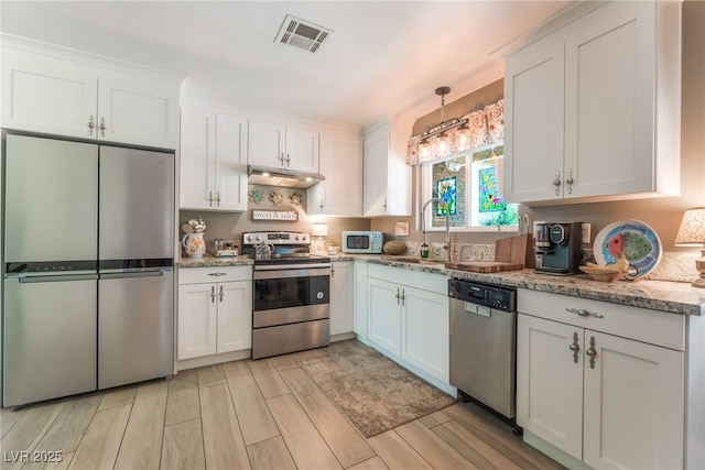 908 Bonita Ave, Las Vegas, NV 89104 - kitchen with stainless steel appliances, under cabinet range hood, white cabinets, wood finish floors, and light stone counters