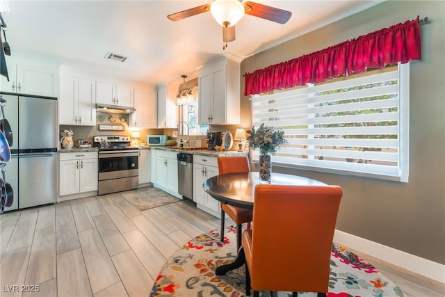 908 Bonita Ave, Las Vegas, NV 89104 - kitchen featuring stainless steel appliances, white cabinets, ceiling fan, light wood-style flooring, and under cabinet range hood