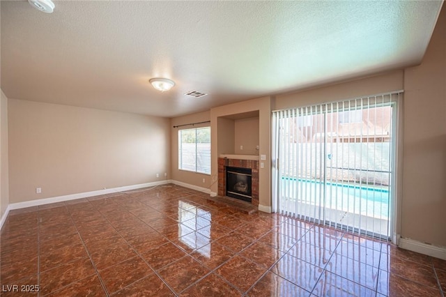 8708 Western Saddle Ave, Las Vegas, NV 89129 - unfurnished living room featuring a tiled fireplace, dark tile patterned flooring, and a textured ceiling