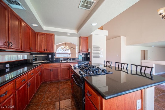 8708 Western Saddle Ave, Las Vegas, NV 89129 - kitchen featuring black range with gas stovetop, a kitchen island, a chandelier, stainless steel microwave, and tasteful backsplash