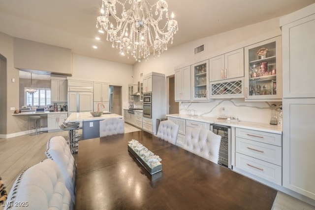 1131 Magic Meadow St, Henderson, NV 89052 - dining room featuring wine cooler, a chandelier, light wood-type flooring, bar, and recessed lighting