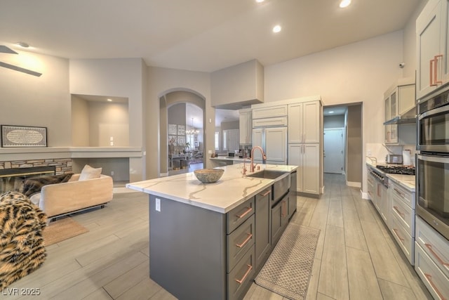1131 Magic Meadow St, Henderson, NV 89052 - kitchen with gray cabinets, arched walkways, light wood finished floors, light stone countertops, and recessed lighting
