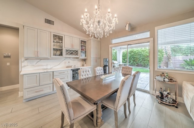 1131 Magic Meadow St, Henderson, NV 89052 - dining space with wine cooler, light wood-style floors, a chandelier, bar, and vaulted ceiling