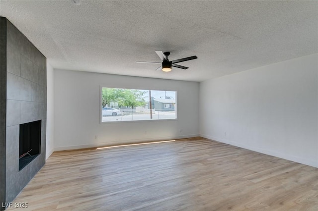 148 Fir St, Henderson, NV 89015 - unfurnished living room featuring light wood-style floors, a ceiling fan, a fireplace, and a textured ceiling