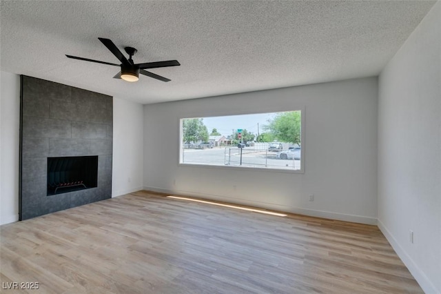 148 Fir St, Henderson, NV 89015 - unfurnished living room featuring a textured ceiling, wood finished floors, a ceiling fan, and a tile fireplace