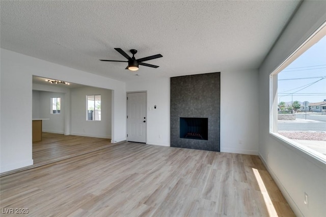 148 Fir St, Henderson, NV 89015 - unfurnished living room featuring a textured ceiling, light wood finished floors, a fireplace, and ceiling fan