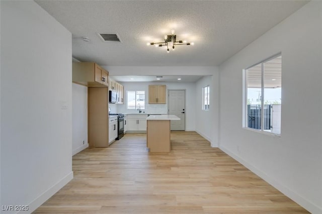 148 Fir St, Henderson, NV 89015 - kitchen with black gas range, a center island, light countertops, light wood finished floors, and a textured ceiling