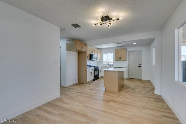 148 Fir St, Henderson, NV 89015 - kitchen featuring black range with gas stovetop, light wood-style floors, stainless steel microwave, a textured ceiling, and a center island