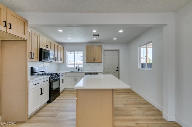 148 Fir St, Henderson, NV 89015 - kitchen with black gas range, stainless steel microwave, light wood finished floors, backsplash, and recessed lighting