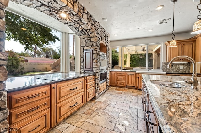7154 Ranchito Cir, Las Vegas, NV 89120 - kitchen featuring stone tile flooring, double oven, brown cabinetry, dark stone counters, and arched walkways