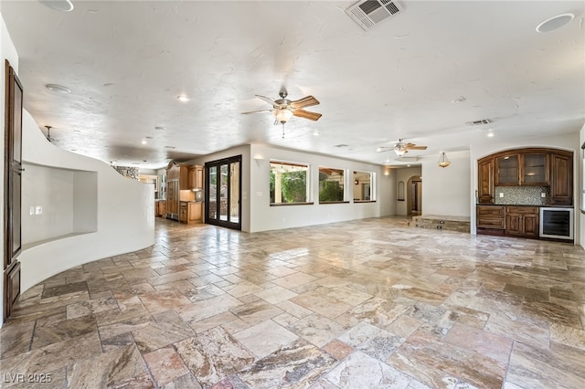 7154 Ranchito Cir, Las Vegas, NV 89120 - unfurnished living room featuring stone tile flooring, beverage cooler, a ceiling fan, recessed lighting, and arched walkways