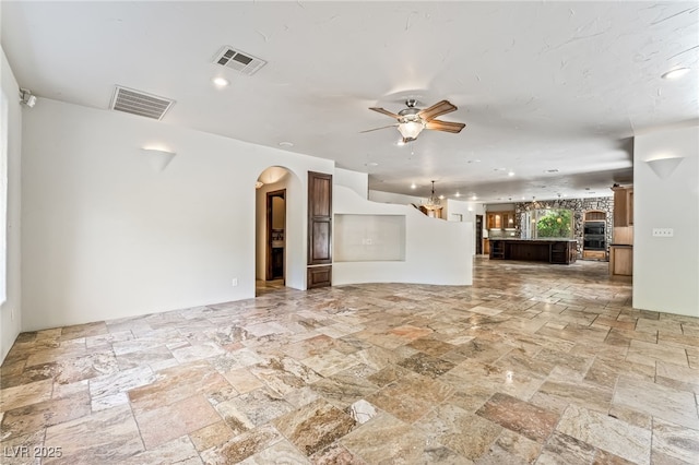 7154 Ranchito Cir, Las Vegas, NV 89120 - unfurnished living room with arched walkways, stone tile flooring, ceiling fan, a chandelier, and recessed lighting