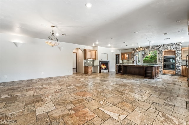7154 Ranchito Cir, Las Vegas, NV 89120 - unfurnished living room with a lit fireplace, arched walkways, and stone tile flooring