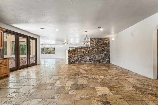 7154 Ranchito Cir, Las Vegas, NV 89120 - unfurnished living room featuring stone tile flooring, ceiling fan, french doors, and arched walkways